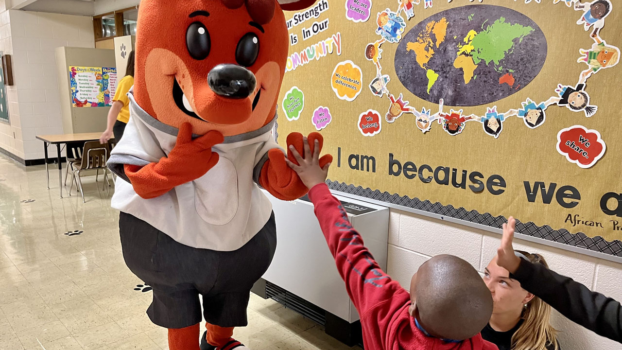 Hog Mollie mascot high-fiving child