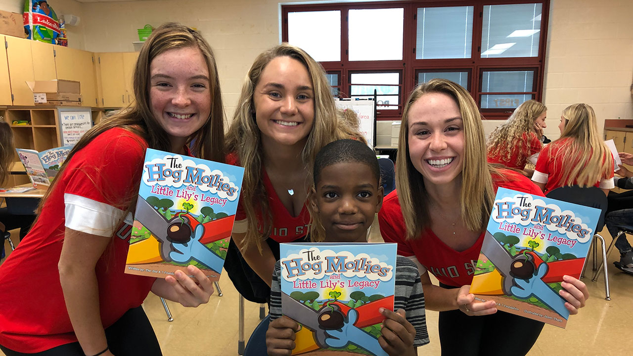 Volunteer Student Athletes standing with child smiling